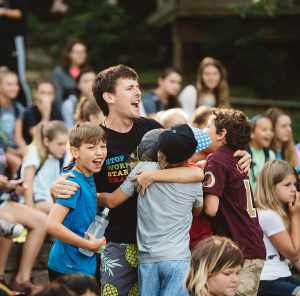 man standing with summer campers and cheering