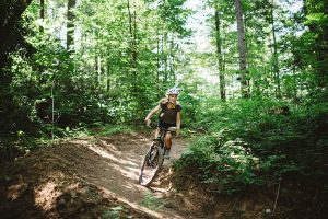 blonde teen girl mountain biking in forest