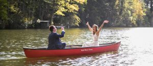 bride and groom in canoe on lake at summer camp wedding