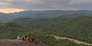 teenagers sitting on rock with view